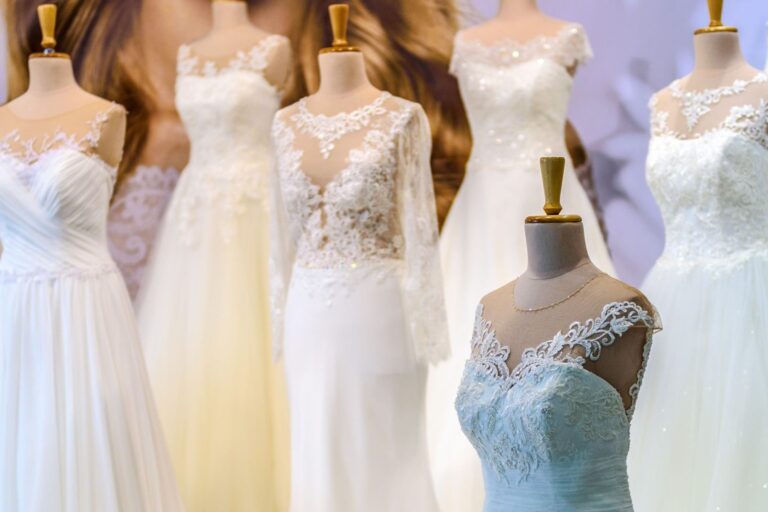 Abiti da sposa in pizzo e tulle su manichini in un'esposizione, con un modello azzurro in primo piano